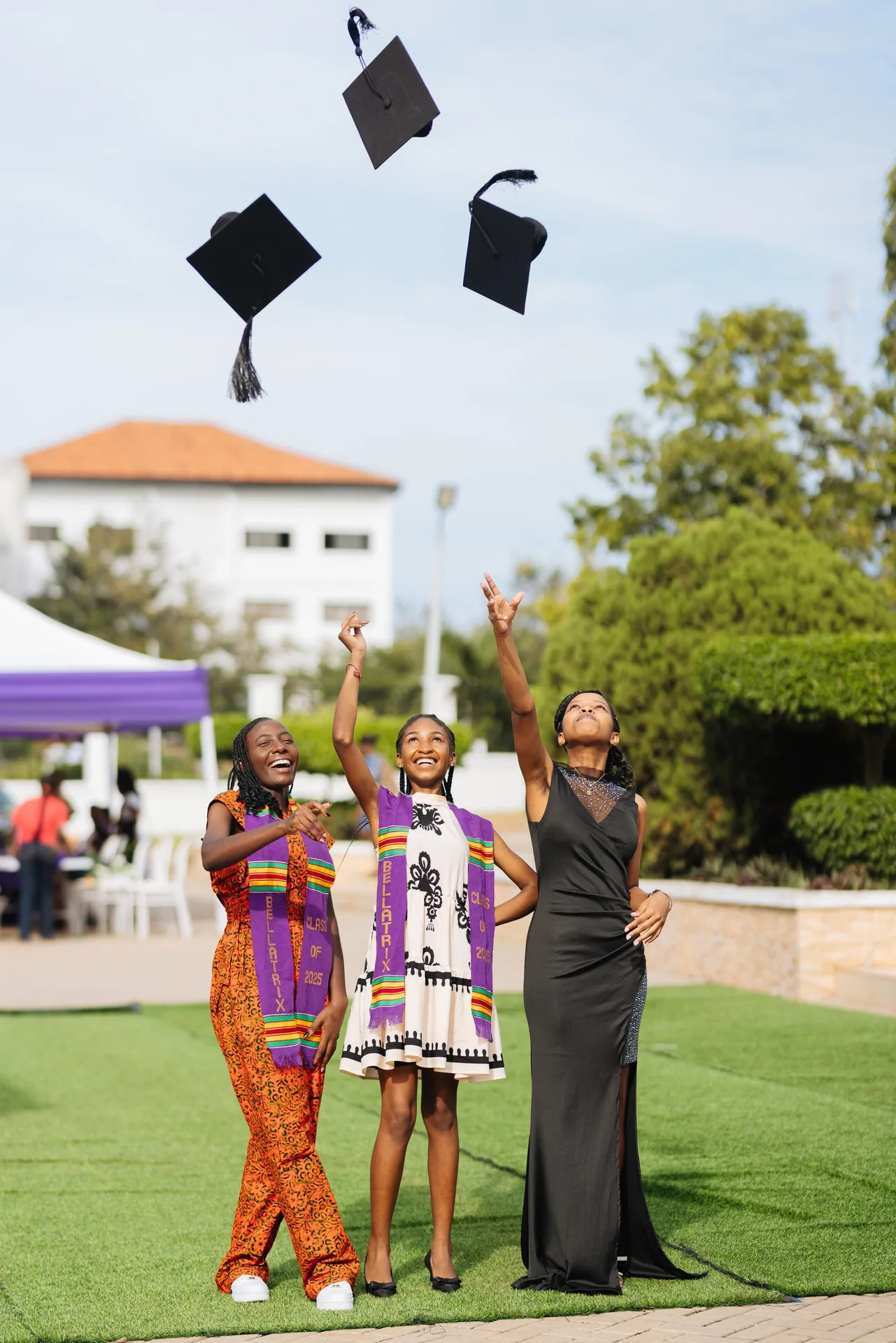 Three ASA graduates throwing their caps into the air