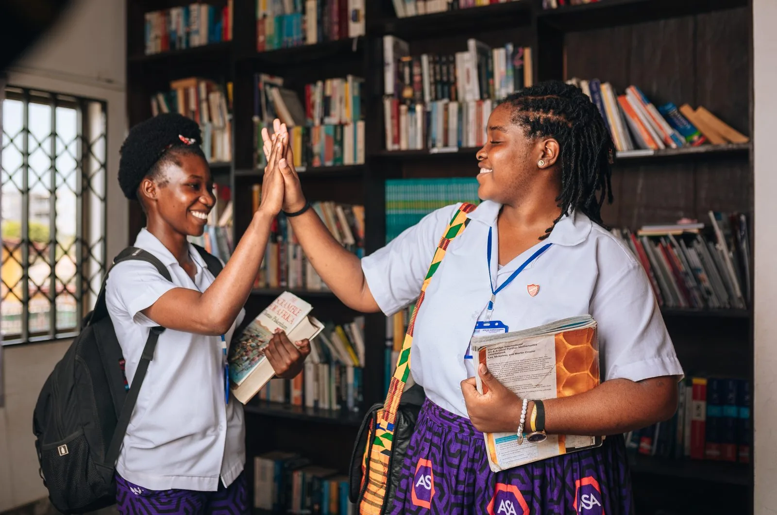 Two ASA students high-fiving in the library