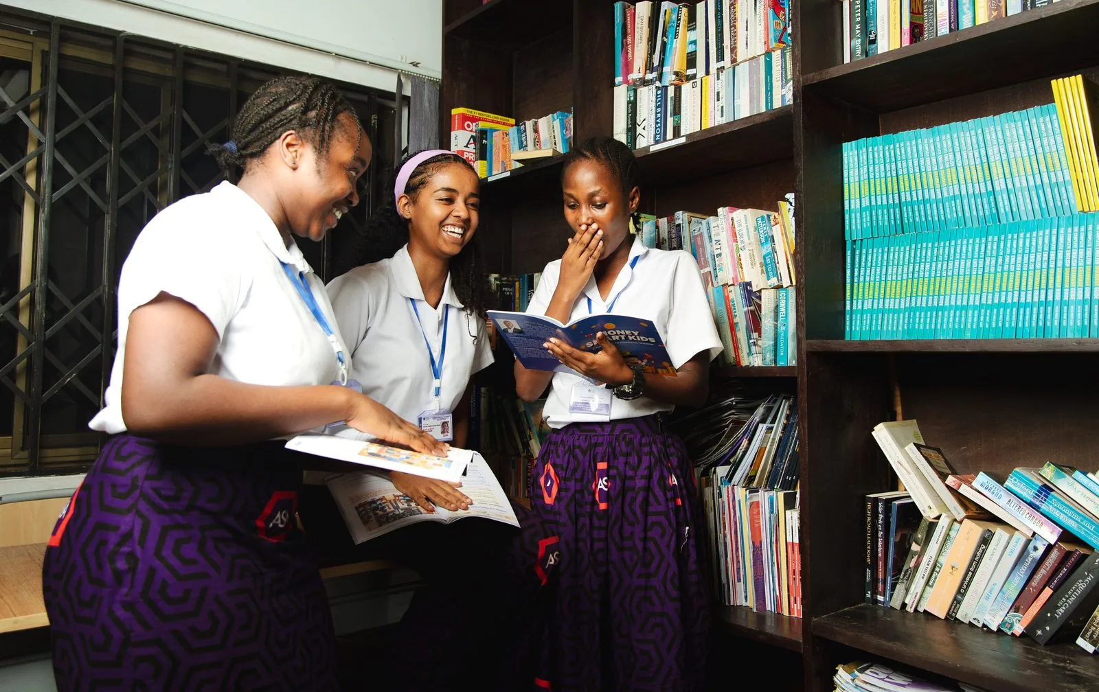 Three ASA students sharing a book together in the library